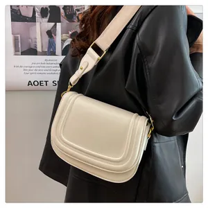 Détail du sac selle crème avec bandoulière large en tissu et boucle en métal doré