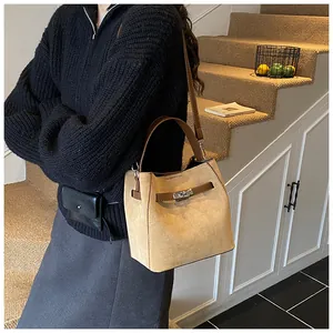 Détail du sac seau en daim camel avec fermoir rotatif argenté et poignée en cuir