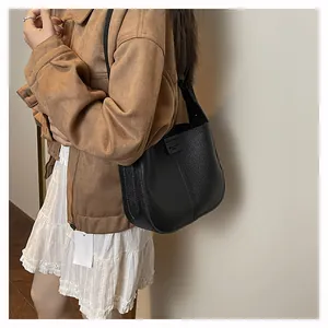 Détail d'un sac à bandoulière en cuir grainé noir avec plaque de marque FEIYU