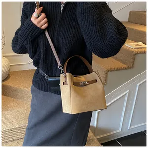 Détail du sac seau en daim camel avec fermoir rotatif argenté et bandoulière en cuir