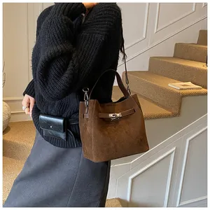 Détail d'un sac seau en daim marron foncé avec fermoir rotatif en métal argenté