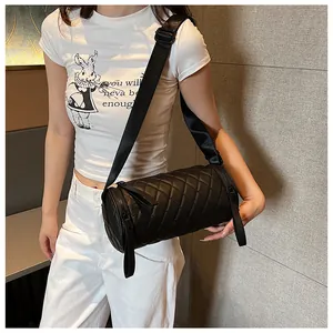 Close-up of a black quilted cylindrical crossbody bag with an adjustable wide strap