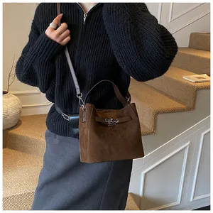 Détails du sac seau en daim marron foncé avec fermoir métallique et bandoulière