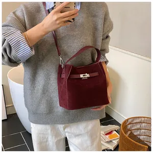 Vue détaillée du sac seau en daim bordeaux avec fermoir argenté et bandoulière amovible