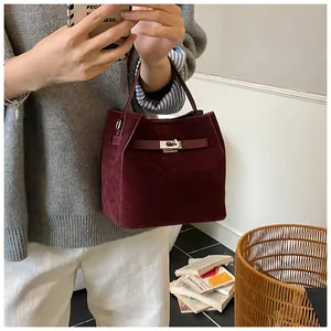 Détail macro du sac seau bordeaux en daim avec fermeture élégante à loquet en métal