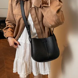 Sac seau minimaliste noir à texture litchi avec bandoulière porté par un mannequin