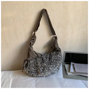 Close-up of brown suede crescent bag with silver sequins and adjustable strap details