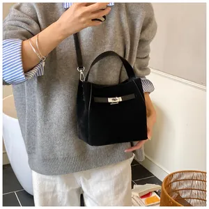 Détail d'un sac seau noir mat avec un fermoir tournant en métal dans un cadre lifestyle