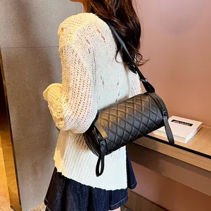 Chic black cylindrical crossbody bag with diamond quilting and leather strap on model