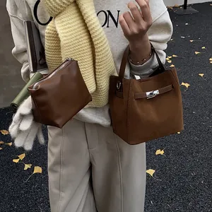 Sac seau vintage en daim marron avec fermoir métallique dans un décor d'automne élégant