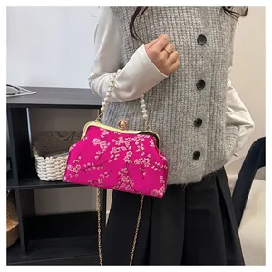 Detail der rosaroten Muscheltasche mit Pflaumenblütenstickerei und Perlengriff