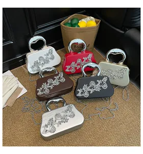 Detalle de flores de pedrería brillante y asas en forma de corazón en bolsos de noche de lujo