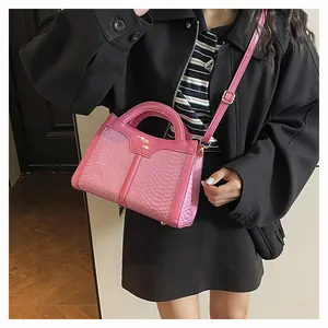 Detail of pink faux-crocodile leather handbag with round handle and metal buckle