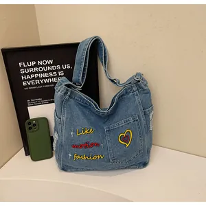 Detail of vintage denim tote bag with letter embroidery and distressed ripped texture