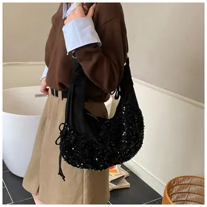 Close-up of a stylish black sequin hobo bag with drawstring details and a crescent shape