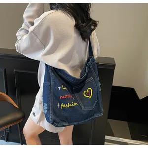 Detailed close-up of blue denim shoulder bag featuring colorful fashion motion embroidery