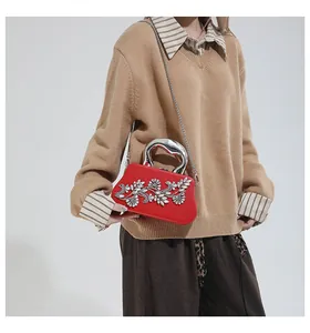 Detalle del bolso de noche rojo con diamantes de imitación florales y asa metálica