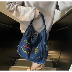 Detailed embroidery on vintage blue denim tote bag with frayed edges and street style