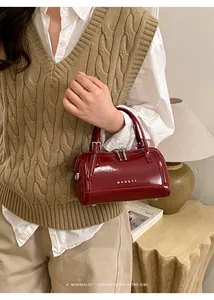 Détail du sac Boston en cuir ciré rouge avec ferrures argentées et texture vintage polie