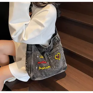 Detailed macro view of gray washed denim bag featuring vintage embroidery and ripped edge