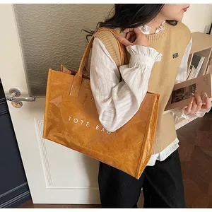 Detail of transparent PVC tote bag with brown inner pouch and bold white text print