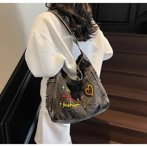 Detail of dark denim crossbody bag with yellow fashion embroidery and star patches