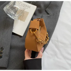 Détail du sac croissant en cuir marron avec anse en chaîne dorée épaisse et fermeture éclair