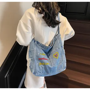 Close-up of blue denim tote bag with red heart embroidery and distressed frayed edges