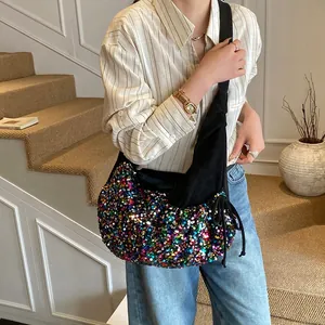 Colorful sequin crescent hobo bag with black wide strap shown on a model in a stylish interior