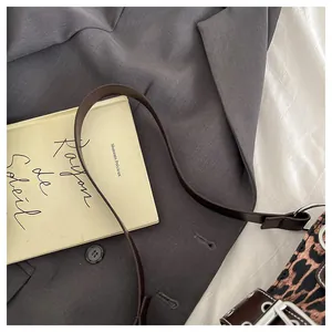 Close-up of leopard print shoulder bag with silver buckle and brown leather strap