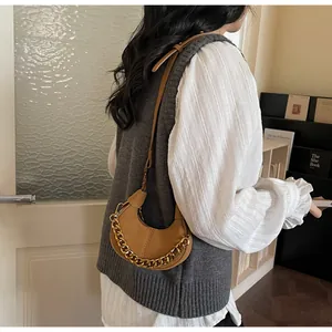 Détail du mini sac croissant camel avec chaîne dorée porté par un mannequin