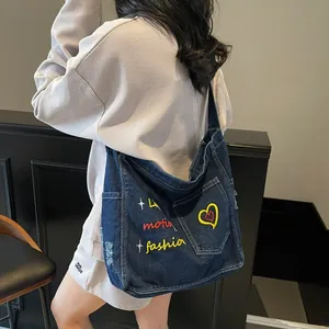 Vintage blue denim hobo bag with colorful embroidery shown on casual street style model