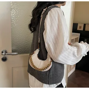 Détail du sac demi-lune crème avec une grosse chaîne dorée et un cuir synthétique texturé