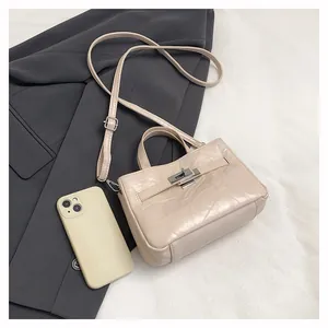 Détail du sac crème avec plis en cuir et boucle métallique à côté d'un téléphone