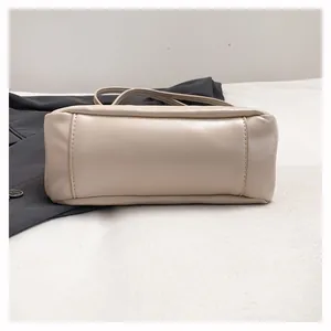 Gros plan sur le fond rectangulaire et les coutures de ce sac à main en cuir crème
