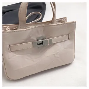 Gros plan du sac crème texturé avec fermoir tournant argenté et détails en cuir plissé