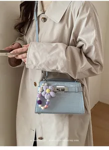 Detail of light blue crocodile embossed handbag with handmade crochet flower charm