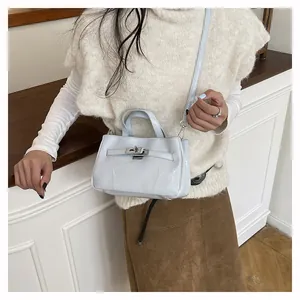 Gros plan d'un mini sac à main bleu clair brillant porté par un mannequin en intérieur