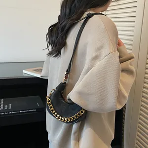 Sac hobo croissant noir avec chaîne dorée épaisse présenté dans un décor de style de vie