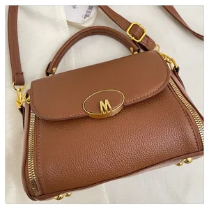 Détail de sac à main en cuir marron avec boucle dorée M et poignée ronde