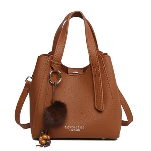 Borsa a mano marrone a grana litchi con tracolla e ciondolo decorativo a pompon