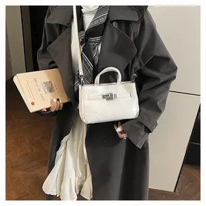 Détail du sac à main blanc gaufré avec fermoir rotatif argenté et texture élégante
