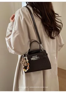 Detailed close-up of dark brown crocodile embossed leather bag with silver metal lock clasp