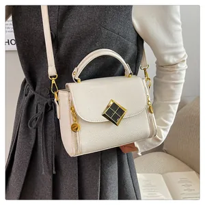 Mini sac bandoulière blanc à motif litchi avec détails dorés porté par un mannequin