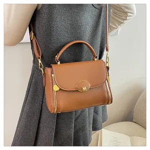 Vue détaillée du sac à main en cuir grainé marron avec logo M doré et fermetures éclair