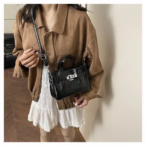 Détail du sac à main en cuir verni noir brillant avec fermoir rotatif et bandoulière