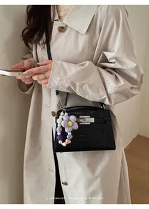 Close-up of black crocodile pattern Kelly bag with purple crochet flower charm