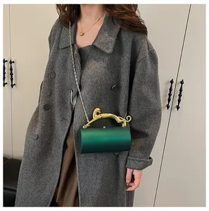Detail of dark green cylinder bag with golden leopard handle and metal chain