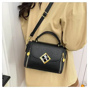 Détail d'un sac à main noir en cuir grainé avec boucle dorée et zips décoratifs