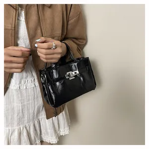 Détail du sac à main en cuir verni noir avec boucle et fermoir métalliques argentés